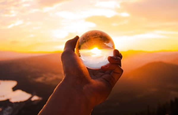 hand holding glass ball reflecting sunlight